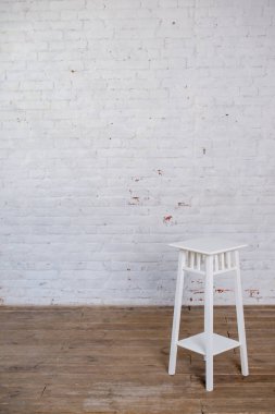 Beyaz bar taburesi beyaz tuğla duvara karşı..