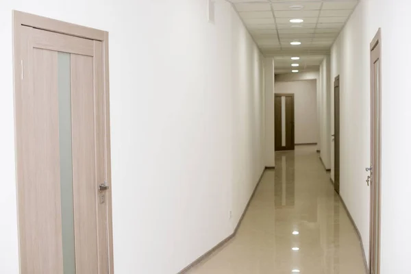 Boş ofis koridoru ve bir sürü odun kapısı var..
