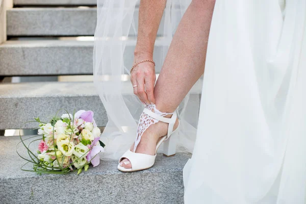 Closeup of bride feet shoes and wedding bouquet of flowers