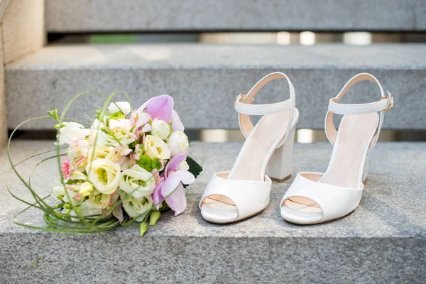 Closeup of bride feet shoes and wedding bouquet of flowers