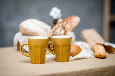 Masanın üzerinde kahverengi seramik kahve fincanı ile sepet fırın ürün çeşitliliği ile kompozisyon