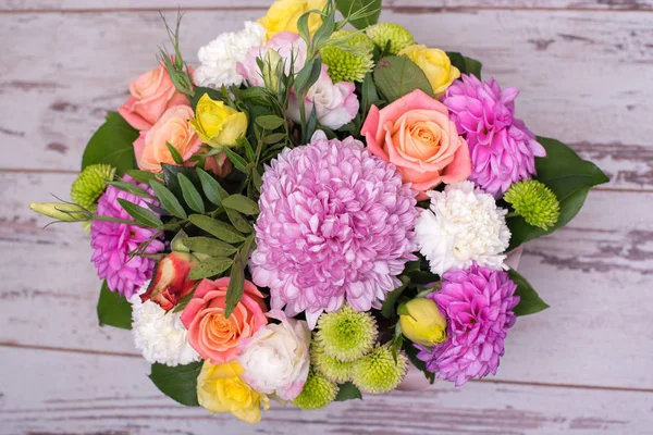 güzel çiçek aranjmanı kutusu, pembe ve sarı gül, pembe eustoma, yeşil ve pembe krizantem, beyaz karanfil, dahlia ahşap arka plan, üstten görünüm üzerinde metin için yer.