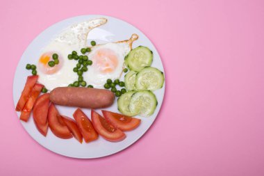 Pembe bir arka plan üzerinde beyaz bir tabakta sosis ile ev yapımı kızarmış yumurta. Klasik kahvaltı. Yukarıdan görüntülemek