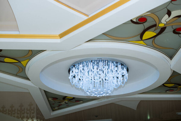 elegant crystal chandelier. White ceiling with windshields.