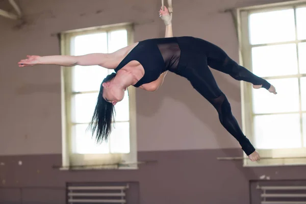 Hermosa gimnasia aérea chica. Artista circo en las correas aéreas con músculos fuertes en el fondo de la ventana.. Fotos De Stock Sin Royalties Gratis