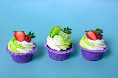 Üç tane krem şantili kek, çikolata, çilek, mavi arka planda süslü badem kurabiyesi. Menü ya da şekerleme kataloğu için resim. metin için boşluk ile.