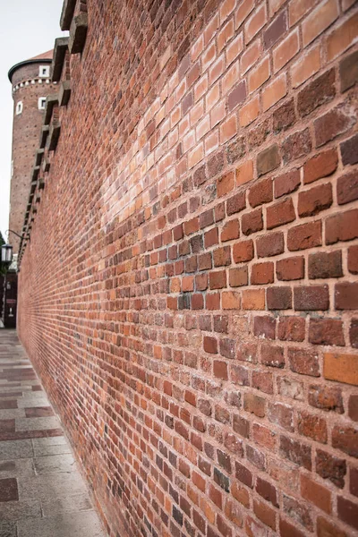 Large wall of small brick near tower. Side view of wall of red brick. Wawel Krakow