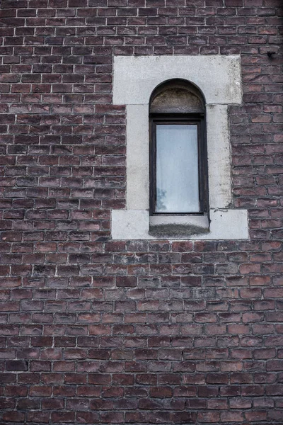 Old wall with window. Ancient window on dark brick wall