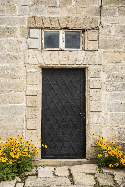 Flowers near iron door. Old black door and yellow flowers