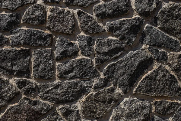 Black stone background. Dark stone fence close-up