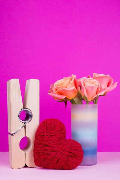 Large clothespin, heart, flowers in vase. Roses in vase and decorations on 14 february day. St. Valentine\'s Day