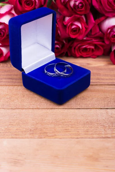 Blue box with jewels and red flowers. Roses, gift box, rings, place for text.