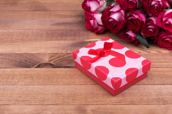 Red box with bow, roses, place for text. Beautiful roses and gift box