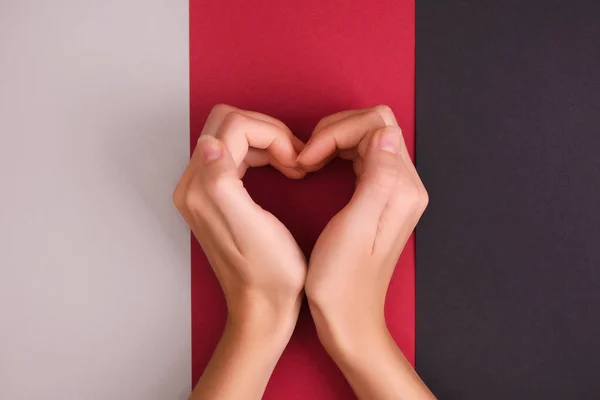 Hands make heart shape on tri-color background