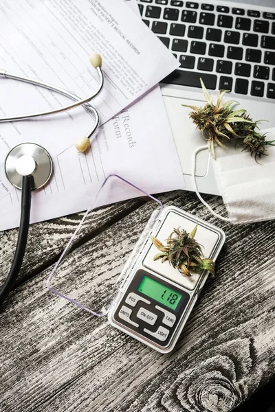 Medical marijuana on the doctor table - medical records, laptop, stethoscope, mask and scales
