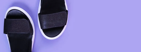 Dark sandals with white soles on a light purple background with place for text banner