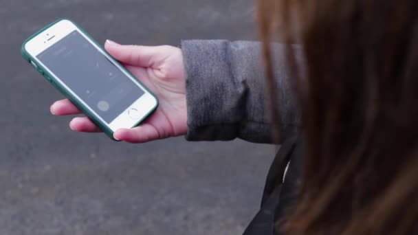 A young girl answers a call with her finger on the touchscreen. She uses a smartphone, holding it in her hand. Closeup girl takes an incoming call from mom. — Stock Video