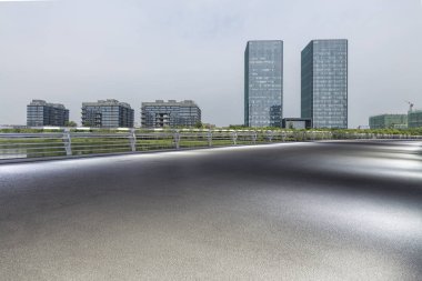 Panoramik siluet ve boş yolu, boş beton zemini olan modern iş binaları.