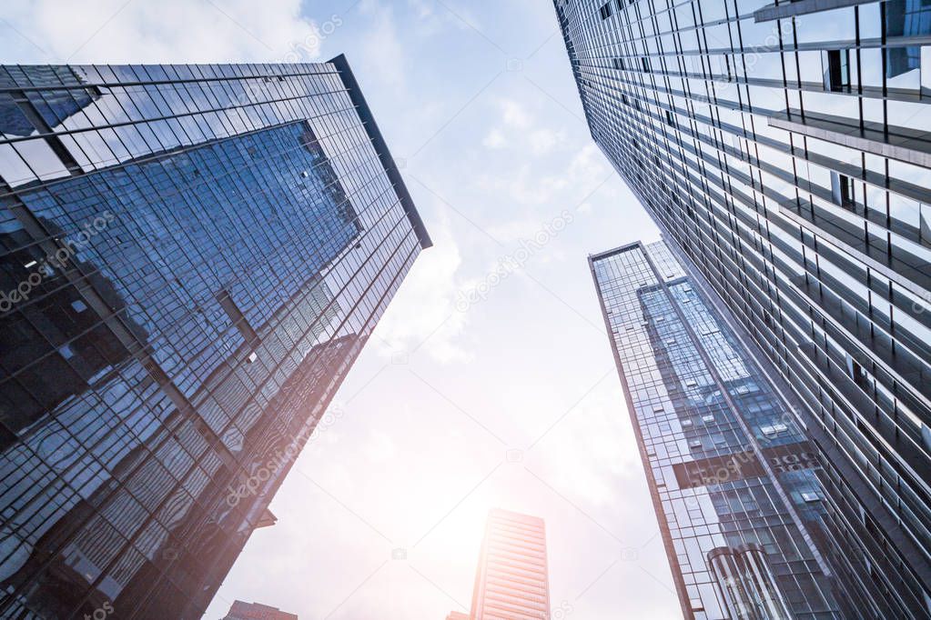 Bottom view of modern skyscrapers in business district against blue sky