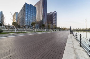 Panoramik siluet ve boş yolu, boş beton zemini olan modern iş binaları.