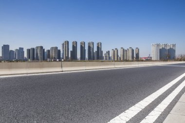Panoramik siluet ve boş yolu, boş beton zemini olan modern iş binaları.