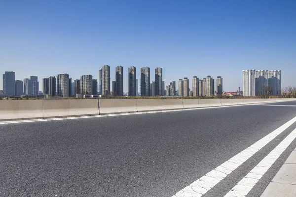 Panoramik siluet ve boş yolu, boş beton zemini olan modern iş binaları.
