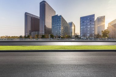 Panoramik siluet ve boş yolu, boş beton zemini olan modern iş binaları.