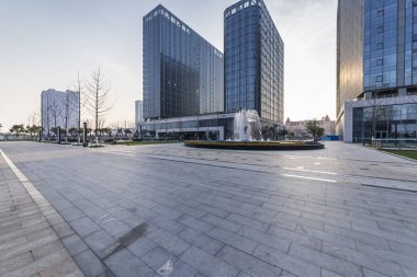 Panoramik siluet ve boş yolu, boş beton zemini olan modern iş binaları.