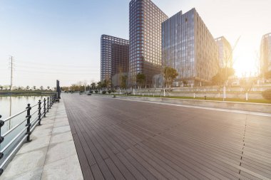 Panoramik siluet ve boş yolu, boş beton zemini olan modern iş binaları.