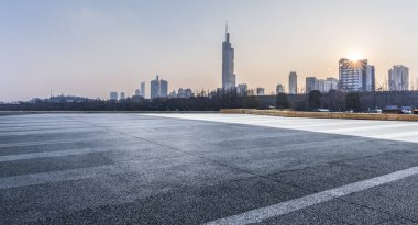 Panoramik siluet ve boş yolu, boş beton zemini olan modern iş binaları.
