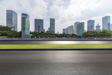 Panoramik siluet ve boş yolu, boş beton zemini olan modern iş binaları.