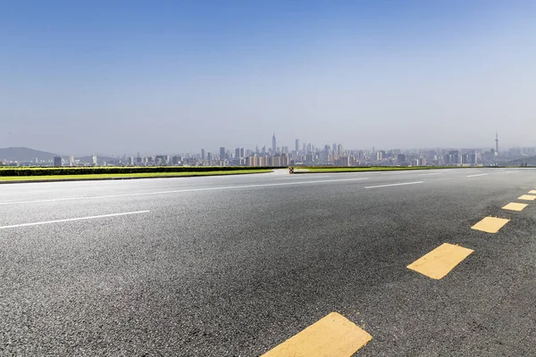 Panoramik siluet ve boş yolu, boş beton zemini olan modern iş binaları.