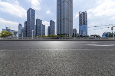 Panoramik siluet ve boş yolu, boş beton zemini olan modern iş binaları.