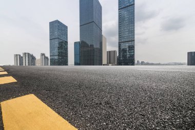Panoramik siluet ve boş yolu, boş beton zemini olan modern iş binaları.