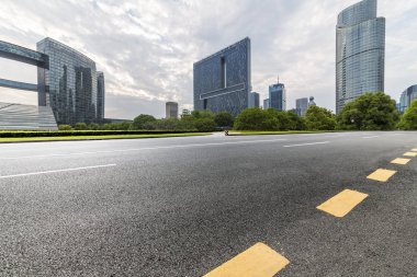 Panoramik siluet ve boş yolu, boş beton zemini olan modern iş binaları.