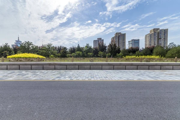 Panoramik siluet ve boş yolu, boş beton zemini olan modern iş binaları.