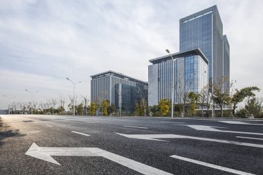 Panoramik siluet ve boş yolu, boş beton zemini olan modern iş binaları.