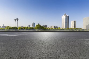 Panoramik siluet ve boş yolu, boş beton zemini olan modern iş binaları.