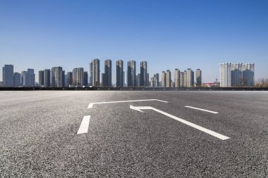 Panoramik siluet ve boş yolu, boş beton zemini olan modern iş binaları.
