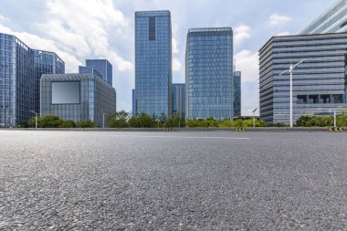 Panoramik siluet ve boş yolu, boş beton zemini olan modern iş binaları.