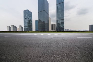 Panoramik siluet ve boş yolu, boş beton zemini olan modern iş binaları.