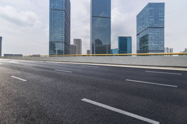 Panoramik siluet ve boş yolu, boş beton zemini olan modern iş binaları.