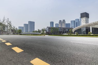Panoramik siluet ve boş yolu, boş beton zemini olan modern iş binaları.