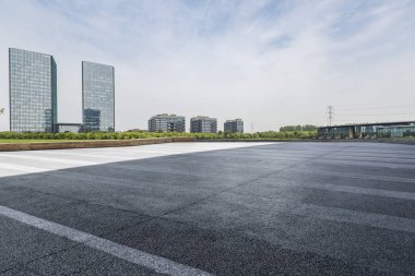 Panoramik siluet ve boş yolu, boş beton zemini olan modern iş binaları.