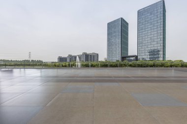 Panoramik siluet ve boş yolu, boş beton zemini olan modern iş binaları.