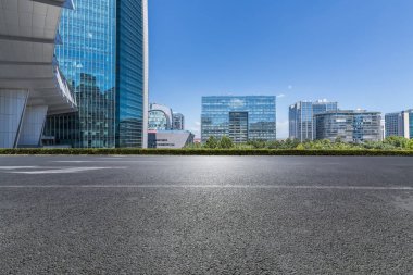 Panoramik siluet ve boş yolu, boş beton zemini olan modern iş binaları.