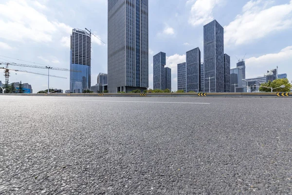 Panoramik siluet ve boş yolu, boş beton zemini olan modern iş binaları.