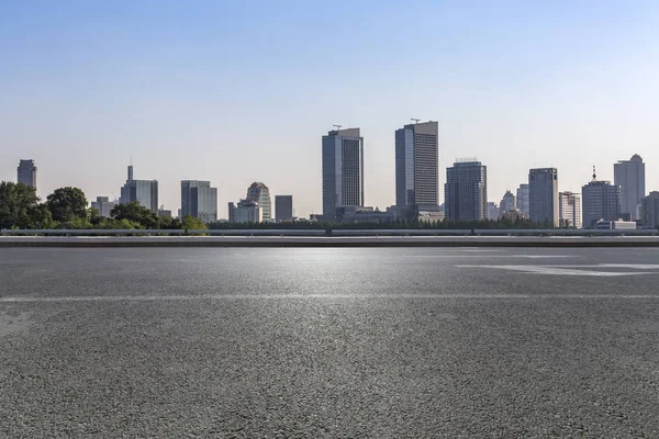 Panoramik siluet ve boş yolu, boş beton zemini olan modern iş binaları.