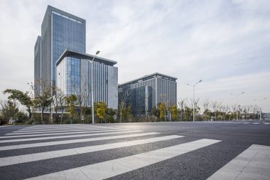 Panoramik siluet ve boş yolu, boş beton zemini olan modern iş binaları.