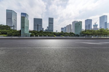 Panoramik siluet ve boş yolu, boş beton zemini olan modern iş binaları.